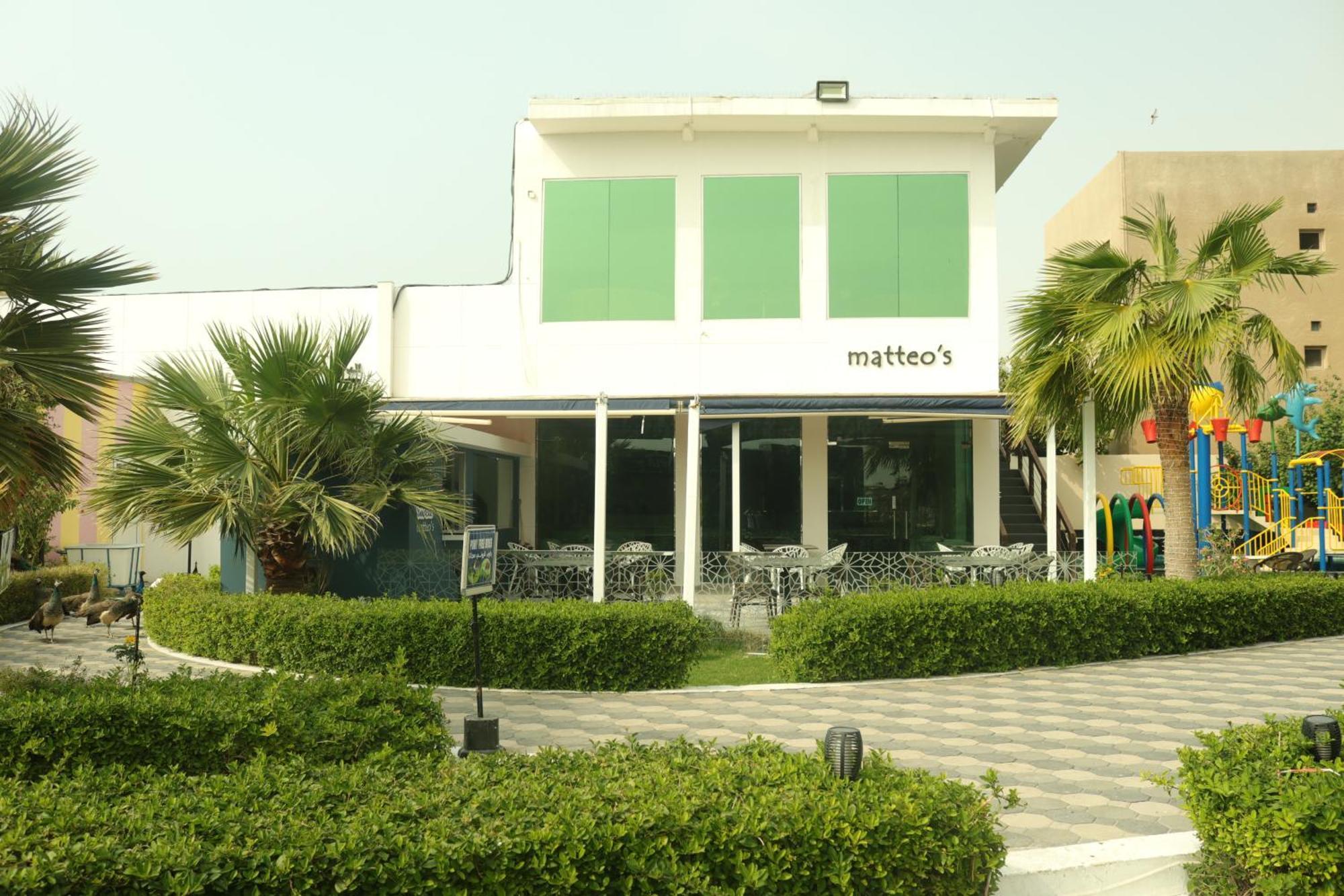 ลากูนา บีช ลักซัวรี รีสอร์ต แอนด์ สปา Hotel มานามา ภายนอก รูปภาพ The photo shows a building with the name "matteo's" displayed prominently on the front. The structure features large windows and green shutters. There is a landscaped area in front with bushes and palm trees, along with a paved pathway leading up to 