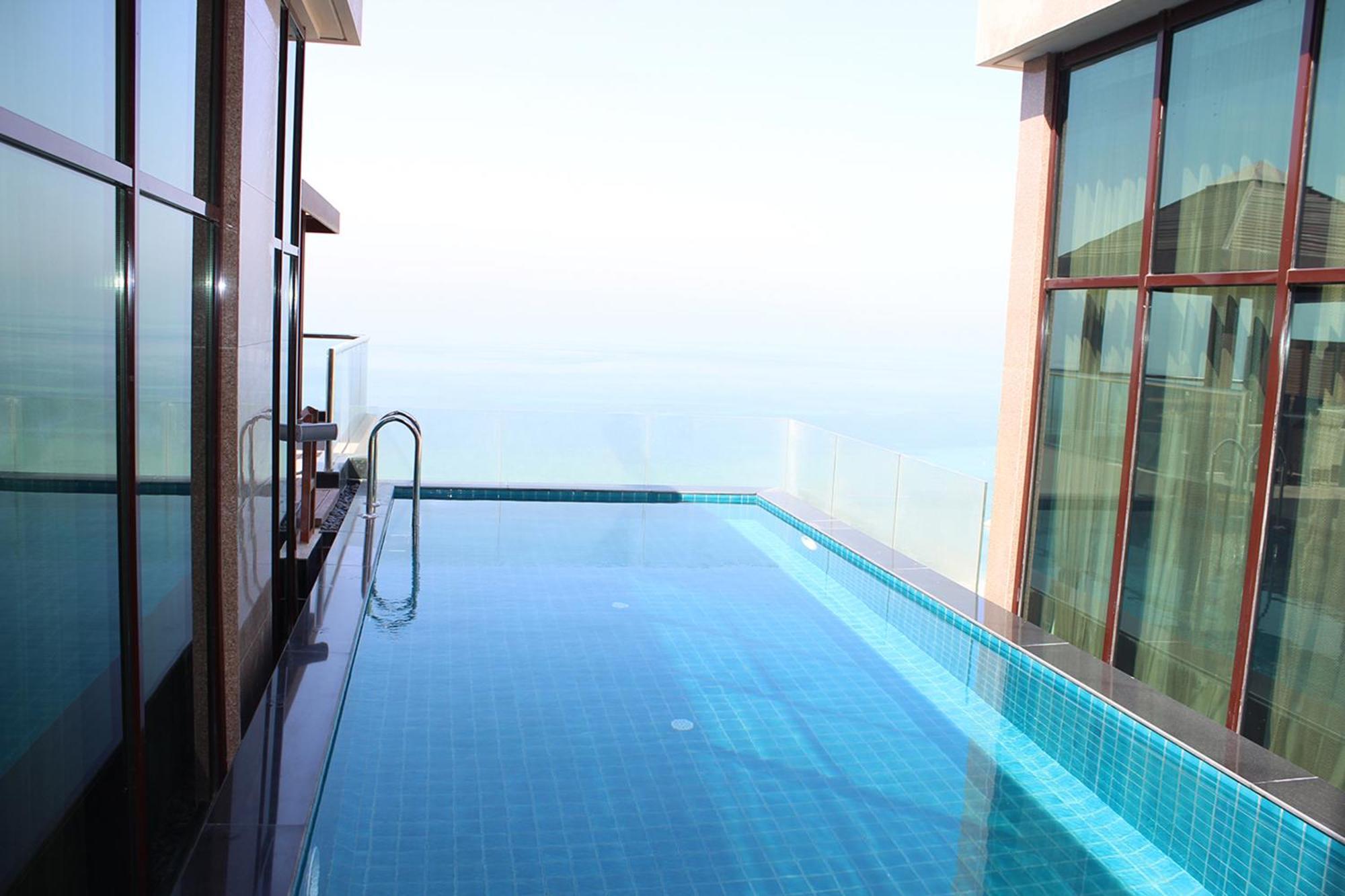 ลากูนา บีช ลักซัวรี รีสอร์ต แอนด์ สปา Hotel มานามา ภายนอก รูปภาพ The photo shows an infinity pool situated on a balcony or rooftop, with a clear view extending to the horizon. The pool has a sleek design with blue tiles, and it appears to be reflecting the sky. There is a ladder on one side for access into the poo