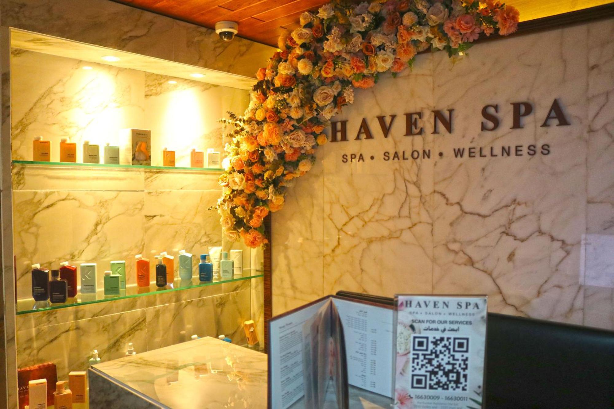 ลากูนา บีช ลักซัวรี รีสอร์ต แอนด์ สปา Hotel มานามา ภายนอก รูปภาพ The photo shows the interior of a spa called "Haven Spa." The wall is decorated with beautiful artificial flowers, creating an inviting atmosphere. There are several shelves displaying various colorful bottles and products, likely for skincare or wel