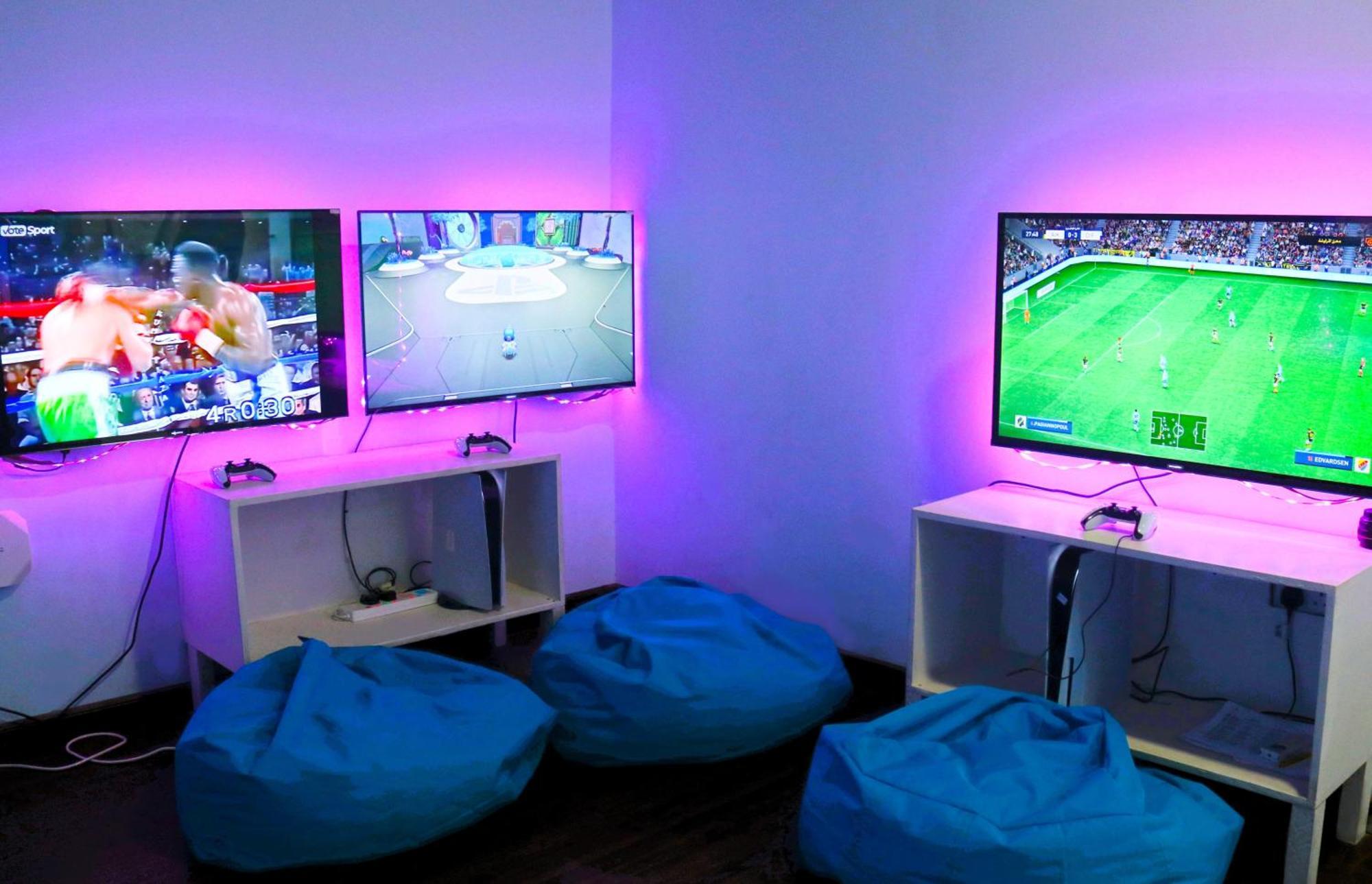 ลากูนา บีช ลักซัวรี รีสอร์ต แอนด์ สปา Hotel มานามา ภายนอก รูปภาพ The photo shows a gaming area featuring three televisions mounted on the wall, displaying different games. Two of the TVs are showing gaming scenes, with one depicting a boxing game and the other showing a vibrant game environment. The third TV displ