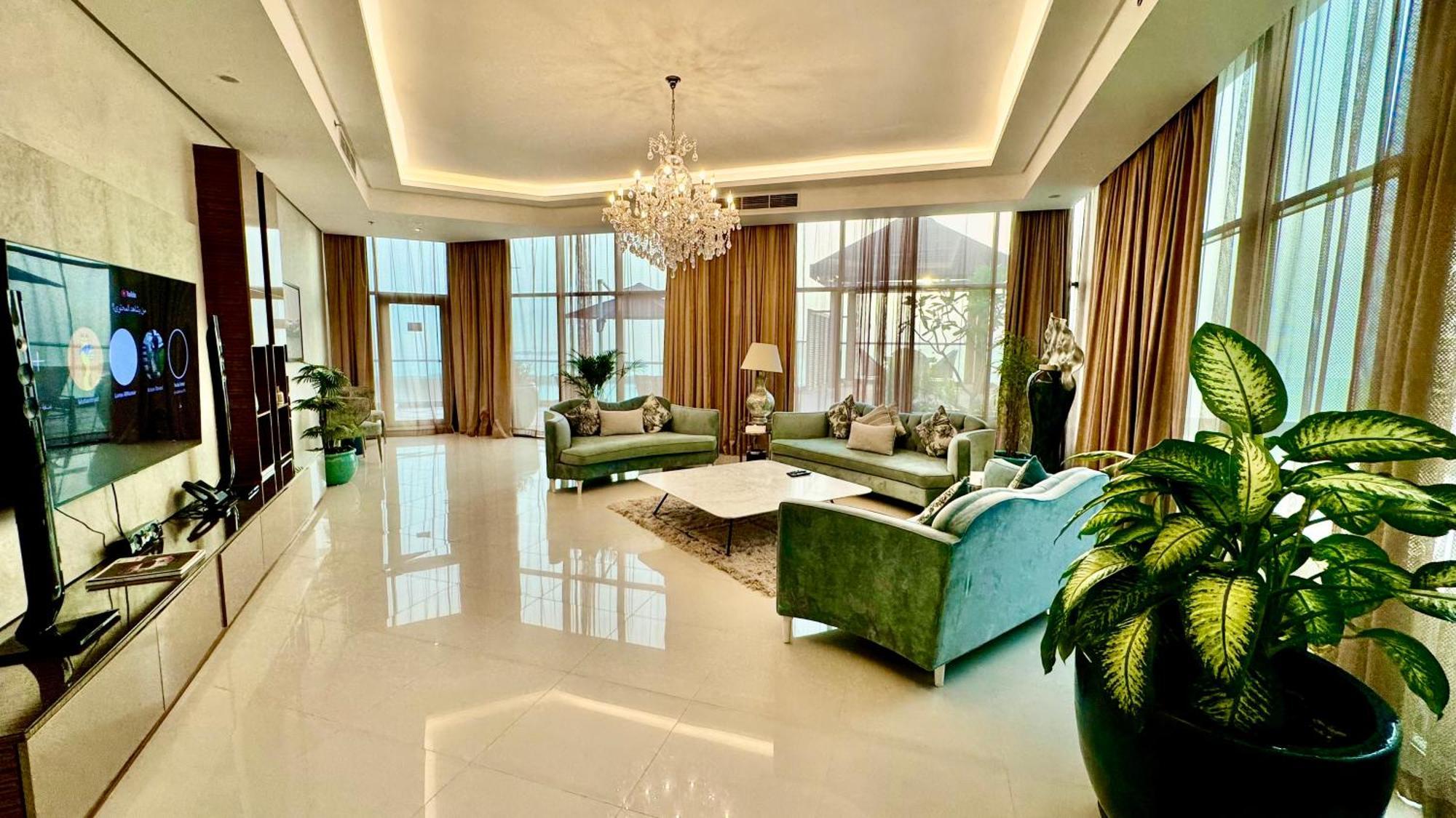 ลากูนา บีช ลักซัวรี รีสอร์ต แอนด์ สปา Hotel มานามา ภายนอก รูปภาพ The photo depicts a spacious and elegantly designed living room. The room features large windows allowing natural light to flood in, accompanied by sumptuous curtains. The furniture includes a pair of soft green sofas and a centerpiece coffee table s