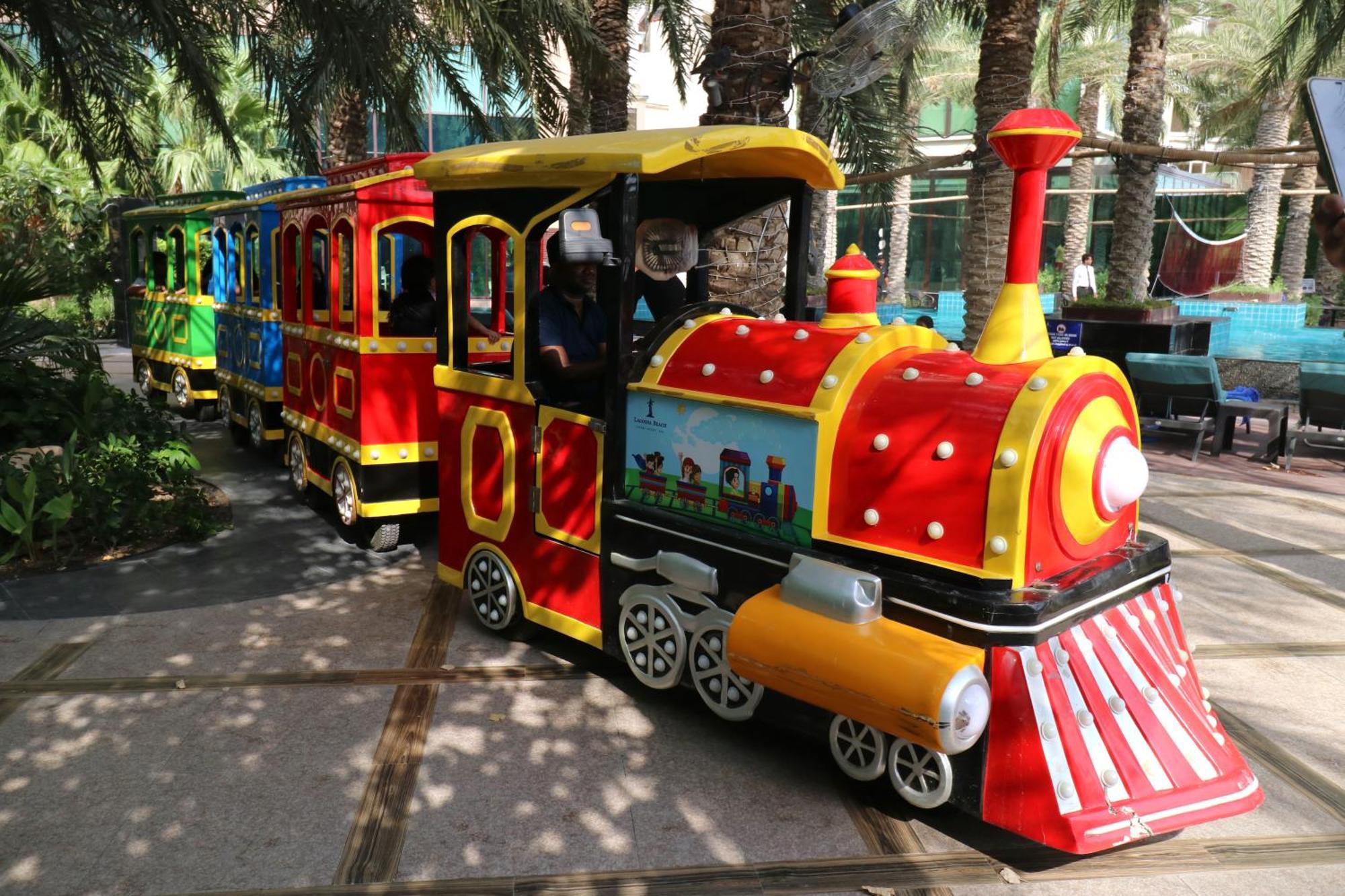 ลากูนา บีช ลักซัวรี รีสอร์ต แอนด์ สปา Hotel มานามา ภายนอก รูปภาพ The photo shows a colorful miniature train. It features a vibrant design with bright red, yellow, and blue colors. The front of the train resembles a classic steam engine, complete with a prominent smokestack. The train is designed to resemble a fun 
