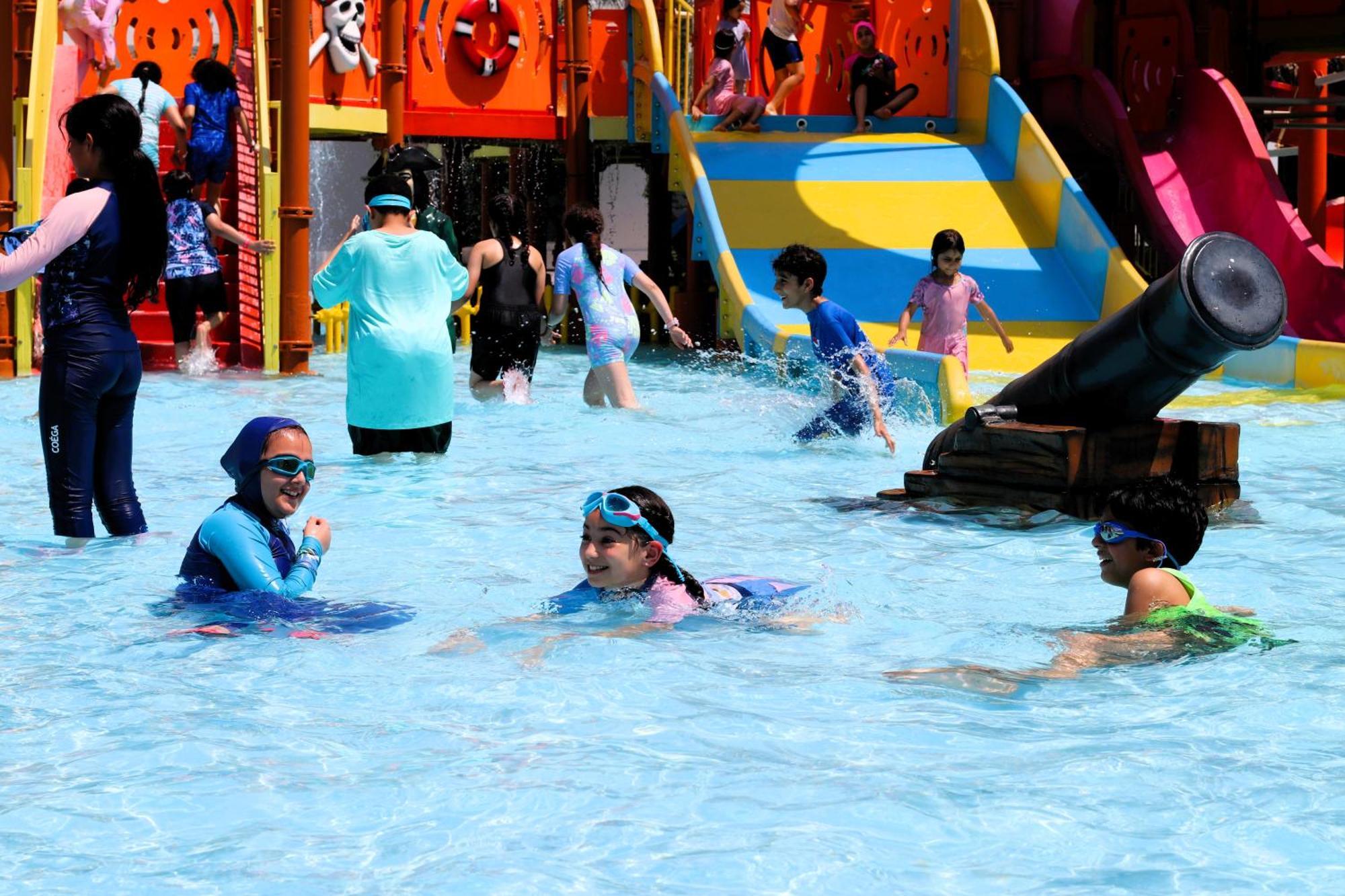 ลากูนา บีช ลักซัวรี รีสอร์ต แอนด์ สปา Hotel มานามา ภายนอก รูปภาพ The photo shows a vibrant water park scene with several children playing in a shallow pool. Some are swimming and splashing around, while others are playing on colorful slides in the background. The atmosphere is lively and cheerful, with kids of var