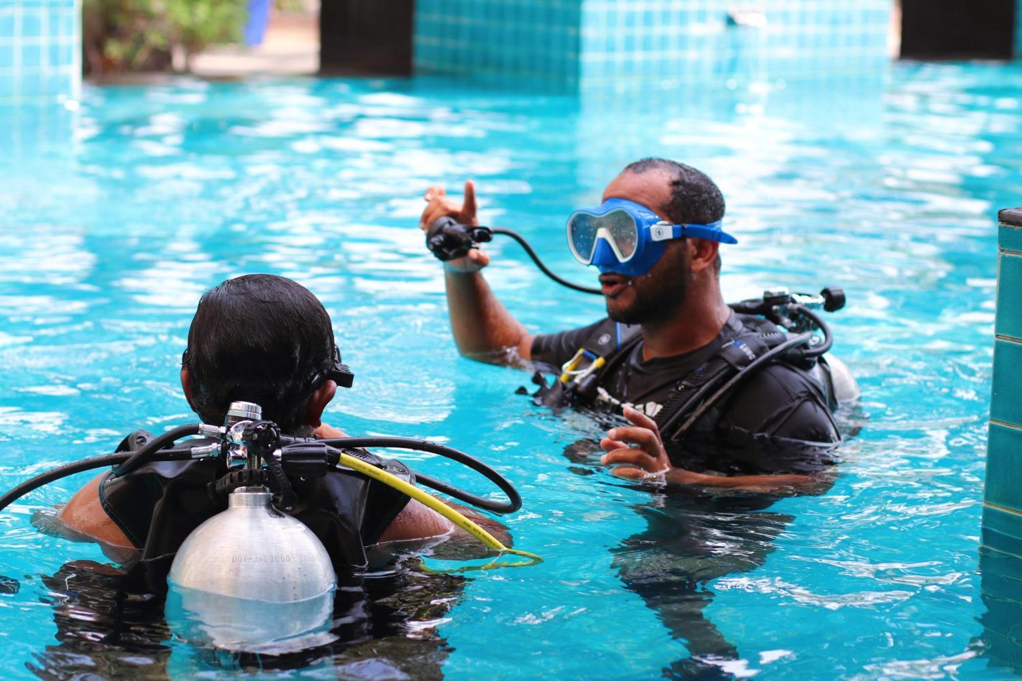 ลากูนา บีช ลักซัวรี รีสอร์ต แอนด์ สปา Hotel มานามา ภายนอก รูปภาพ The photo shows two divers in a pool. One diver is wearing a scuba mask and is speaking to the other diver, who is also equipped with scuba gear. They appear to be engaged in a discussion, possibly related to diving instructions or safety. The water 