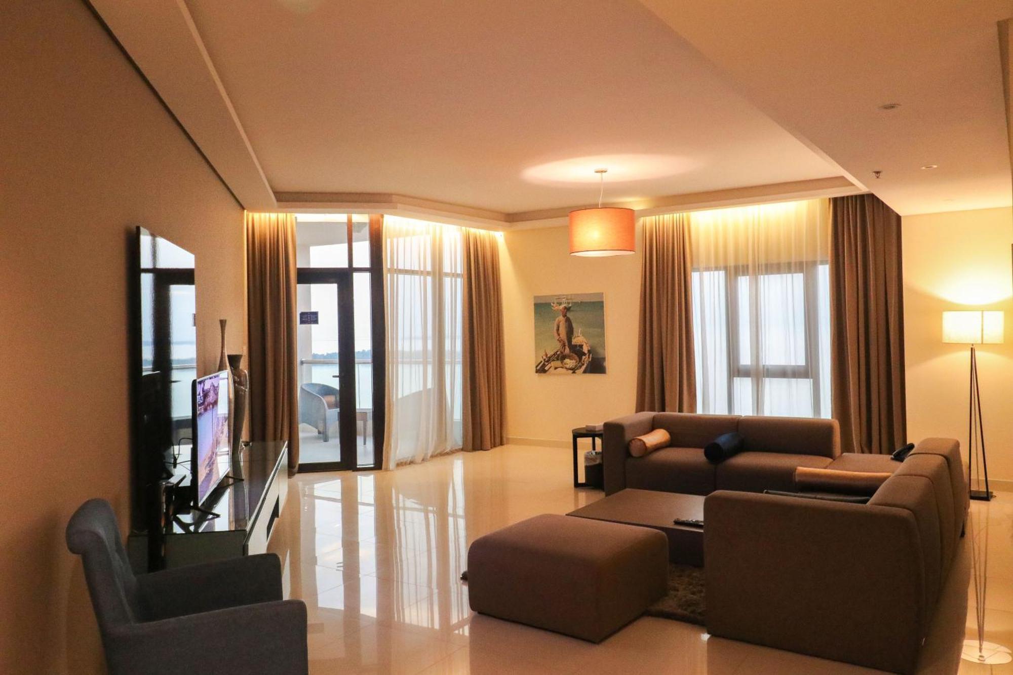 ลากูนา บีช ลักซัวรี รีสอร์ต แอนด์ สปา Hotel มานามา ภายนอก รูปภาพ The photo shows a modern living room with a spacious and elegant design. It features a large couch in neutral tones, a soft ottoman, and a stylish coffee table. The walls are painted in a light color, and there are large windows with sheer curtains a