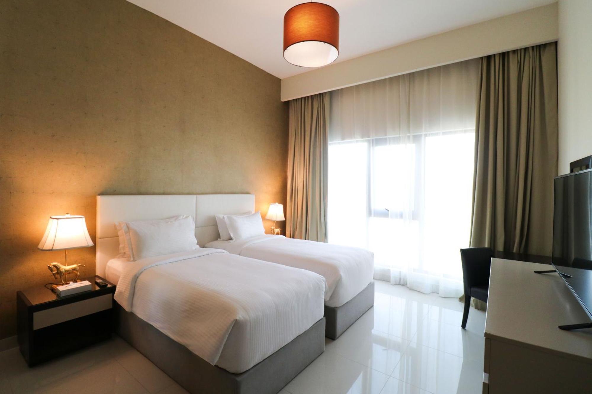 ลากูนา บีช ลักซัวรี รีสอร์ต แอนด์ สปา Hotel มานามา ภายนอก รูปภาพ The photo shows a hotel room featuring two single beds with white bedding. The walls have a neutral tone, and there's a large window covered by light, sheer curtains allowing natural light to enter. On either side of the beds, there are bedside table